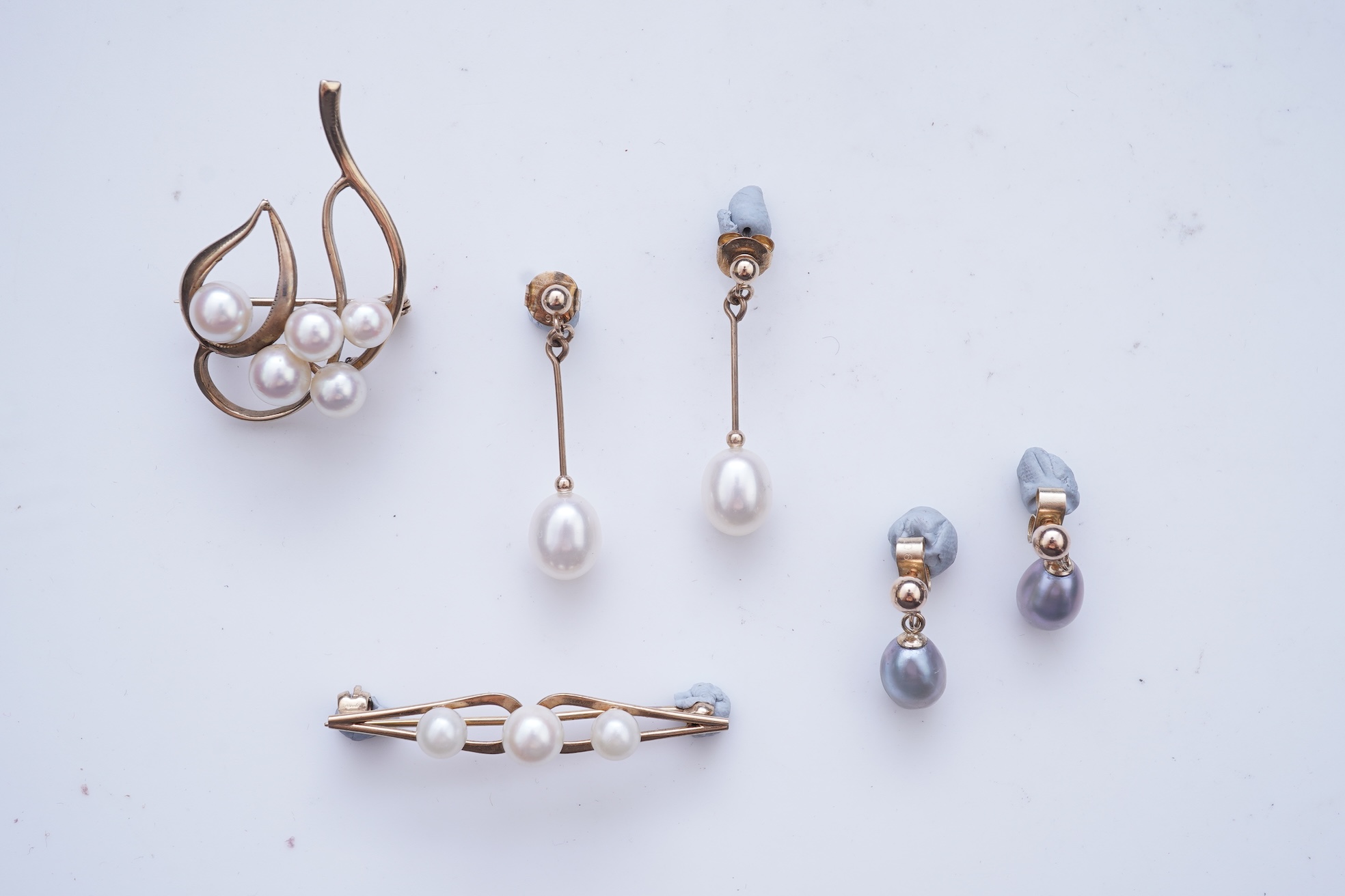 A group of cultured pearl jewels, comprising: two pairs of cultured pearl drop earrings, longest 3cm, mounted in gold; and two cultured pearl brooches mounted in 9ct gold, longest 4.1cm, British hallmarks, combined gross